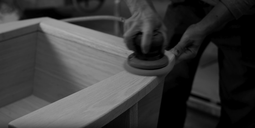 Cover Image of the video showing how our furniture is handmade with a man's hand sanding one of the pieces
